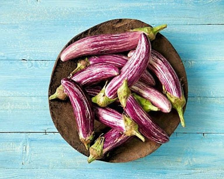 Berinjela Japonesa: Sem Amargor e Cheia de Versos 1 Berinjelas japonesas roxas escuras com casca brilhante em cesto de bambu