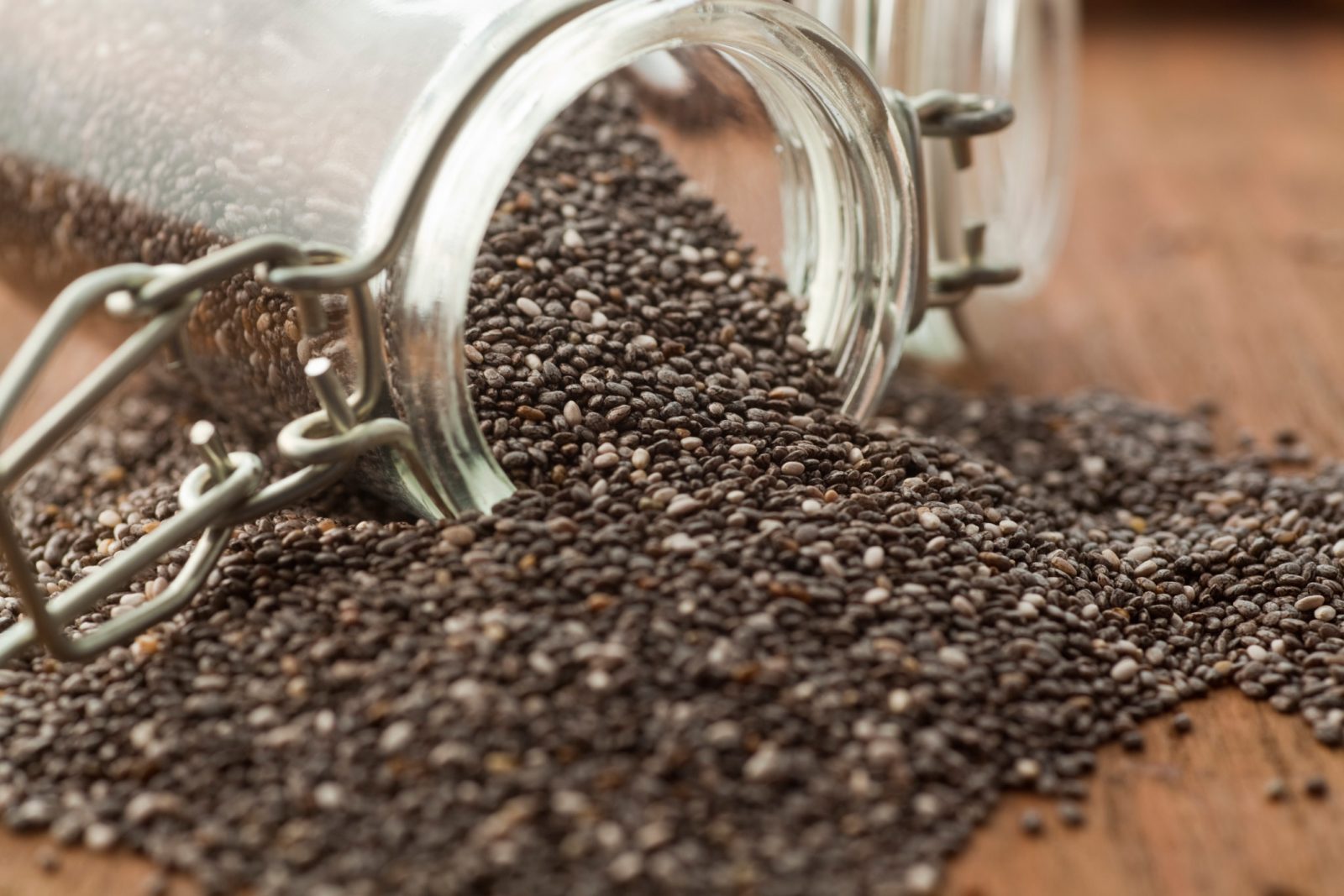 Chia: A Semente Poderosa da Saúde e Saciedade 1 Sementes de chia pretas em recipiente de vidro transparente, com colher de madeira ao lado
