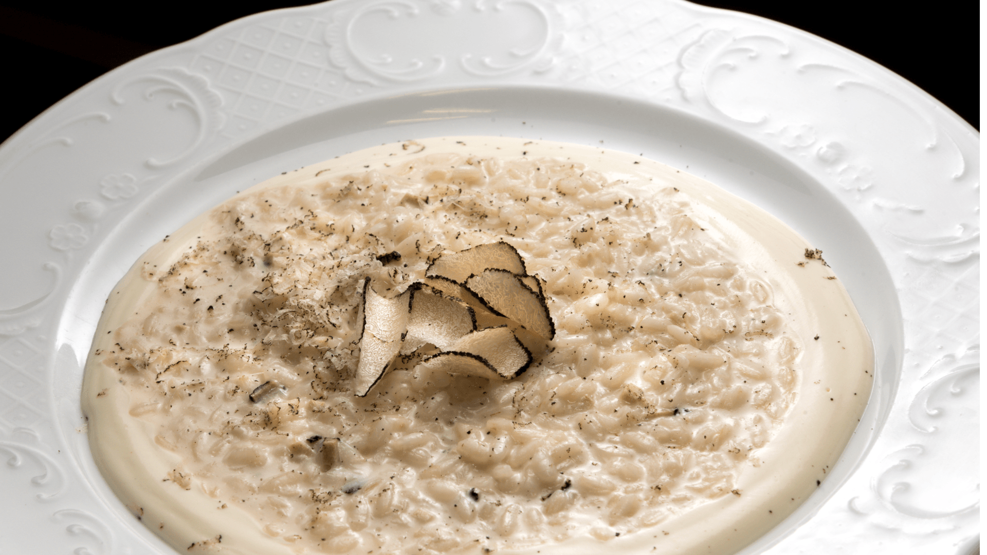 Receita Profissional: Risotto de Azeite Trufado com Parmesão 1 Prato branco com risotto cremoso de cor creme, regado com azeite trufado e decorado com salsinha picada e lascas de parmesão